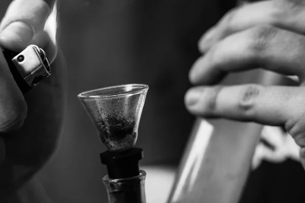 A man smokes bong cannabis weed. Smoke on a black background. Concepts of medical marijuana use and legalization of the cannabis. Black and white — Stock Photo, Image