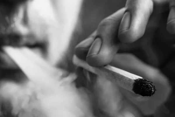 Fumée sur fond noir. Un homme fume de l'herbe de cannabis, un joint et un briquet dans ses mains. Concepts de la consommation de marijuana médicale et de la légalisation du cannabis.Noir et blanc — Photo