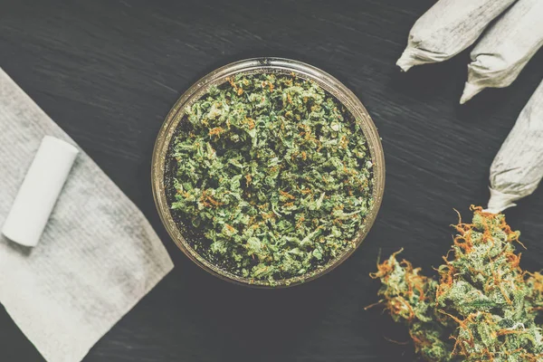 Grinder for chopping cannabis flowers with fresh weed surrounded Matting vintage color — Stock Photo, Image