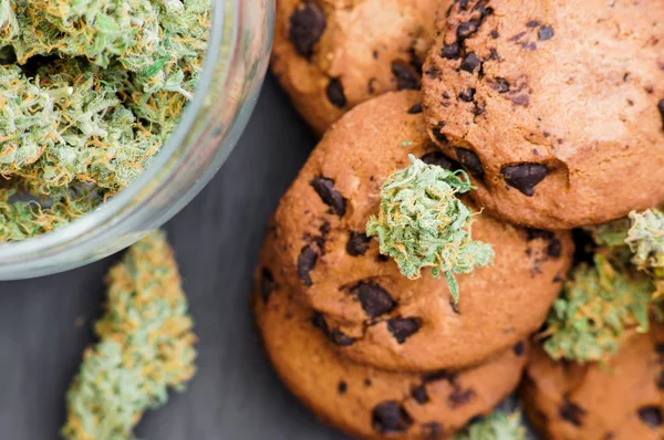 Biscotti con cannabis e germogli di marijuana sul tavolo. Concetto di cucina con erba di cannabis. Trattamento della marijuana medica per uso alimentare, su sfondo nero — Foto Stock