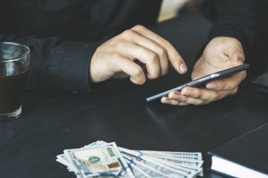Teknoloji, online bankacılık, para transferi, e-ticaret kavramı. Kullanma smartphone dolarlarına gri duvar arka plan üzerinde uçan iş adamı. Internet kazanç kavramı