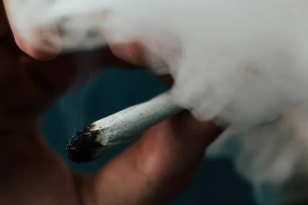 Konopí trávu, spoj ve své ruce A muž kouří. Kouř na černém pozadí. Užívání lékařské marihuany a legalizace konopí. — Stock fotografie
