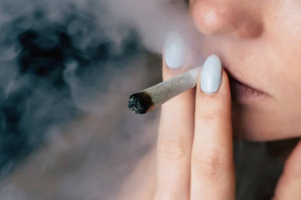 医疗用大麻的概念和大麻的合法化。黑色背景下的烟雾。一个女人吸食大麻大麻, 一个关节和他手中的打火机. — 图库照片