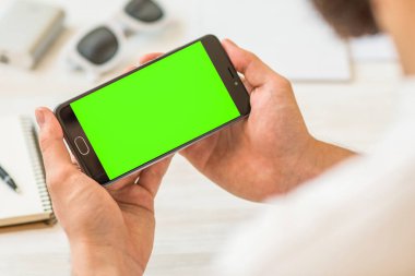 Smartphone için chroma anahtar adam yeşil ekran ile kullanan bir akıllı telefon ile yatay bir siyah kompozisyon Online ödeme plastik kart tutan el ile yeşil ekran