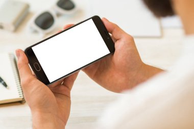 Adam bir akıllı telefon yatay olarak el kredi kartı tutan smartphone Closeup fotoğraf işadamı için beyaz bir ekran ile kullanır ve. Online ödeme plastik kart. Yatay mockup. Bulanık, film etkisi