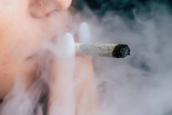 联合在妇女手。一个女人抽大麻杂草, 一个。黑色背景下的烟雾。医用大麻的概念与大麻合法化. — 图库照片