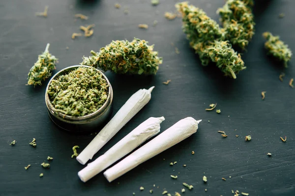 Hierba común Macro de marihuana de brotes de cannabis con tricomas y hierba triturada en una mesa negra de cerca —  Fotos de Stock