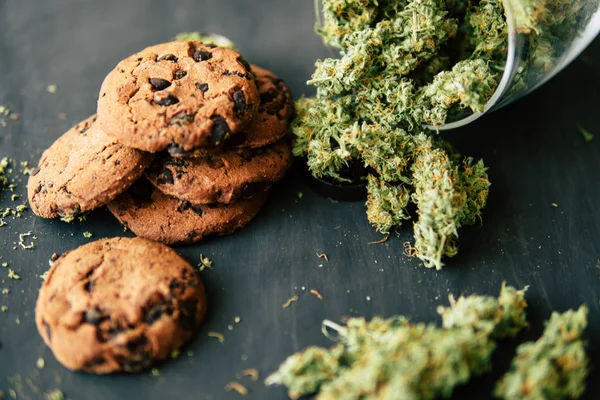 Biscoitos com maconha e botões de maconha na mesa. Conceito de cozinhar com erva de cannabis. Tratamento de maconha medicinal para uso em alimentos, em um fundo preto — Fotografia de Stock