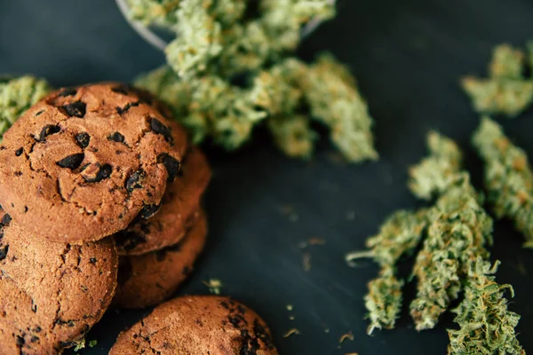 Kannabiszos sütik és marihuána rügyek az asztalon. Fogalom főzés cannabis gyógynövény. Orvosi marihuána kezelése élelmiszerekben, fekete alapon — Stock Fotó