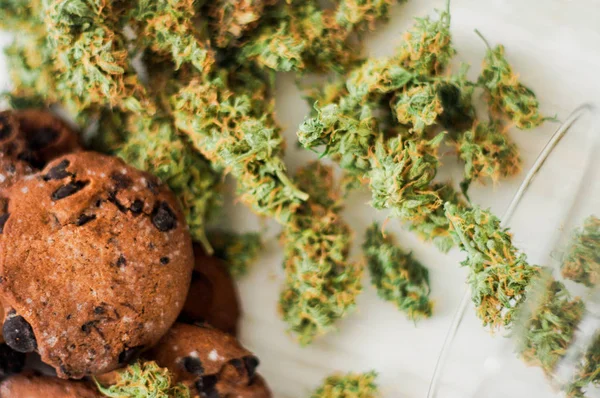 Cookies med cannabis och knoppar av marijuana på bordet. ovanifrån begreppet matlagning med cannabisblad. Behandling av medicinsk marijuana för användning i livsmedel på en vit bakgrund — Stockfoto