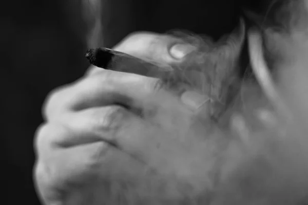 Rookt wiet cannabis, een man die gezamenlijk in zijn handen. Roken op een zwarte achtergrond. Begrippen medisch marihuanagebruik en legalisatie van de cannabis. Zwart-wit — Stockfoto