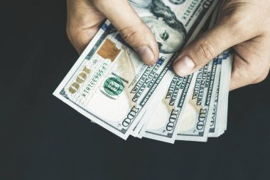 Beyaz genç adam para sayar, yüz yeni banknotlar siyah bir arka plan planı kapatın. İş ve finans kavramları. Üstten Görünüm .