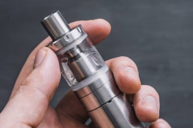 Genç adam vape elektronik sigara bulut vaping aygıt arka plan bir mod, duman püf noktalarını kullanarak.