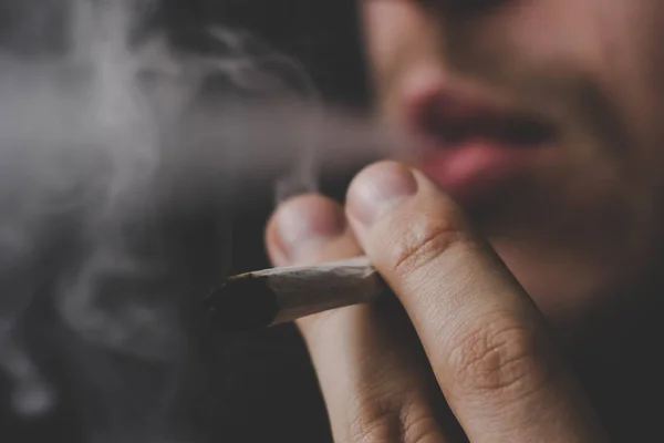 Конопля, косяк в руках, человек курит. Дым на черном фоне. Концепции использования медицинской марихуаны и легализации марихуаны . — стоковое фото
