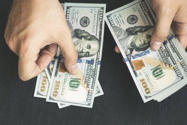 Beyaz genç adam para sayar, yüz yeni banknotlar siyah bir arka plan planı kapatın. İş ve finans kavramları. Üstten Görünüm .