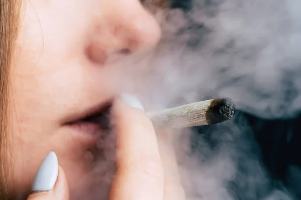 一个女人抽大麻, 一个关节和他手中的打火机。黑色背景下的烟雾。医用大麻的概念与大麻合法化. — 图库照片