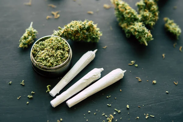 Gezamenlijke onkruid Macro van cannabis toppen marihuana met schubben en geplette onkruid op een zwarte tafel close-up — Stockfoto