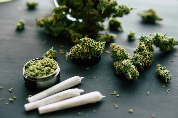 Macro de marihuana de brotes de cannabis con tricomas y hierba aplastada en una mesa negra de cerca — Foto de Stock