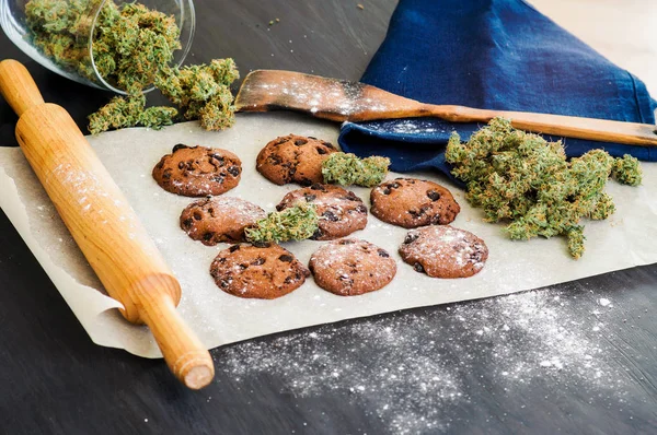 Biscoitos com maconha e botões de maconha na mesa. Conceito de cozinhar com erva de cannabis. Tratamento de maconha medicinal para uso em alimentos, em um fundo preto — Fotografia de Stock