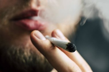 Sigara ve esrar esrar, esrar ve onun elinde bir çakmak. Siyah bir arka plan üzerinde duman. Tıbbi esrar kullanım ve yasallaştırma esrar kavramları.