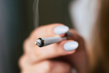 Esrar ot, onun eller A kadın ortak bir çekiyor. Siyah bir arka plan üzerinde duman. Tıbbi esrar kullanım ve yasallaştırma esrar kavramları.