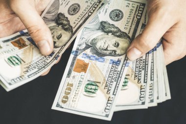 Beyaz genç adam para sayar, yüz yeni banknotlar siyah bir arka plan planı kapatın. İş ve finans kavramları. Üstten Görünüm .