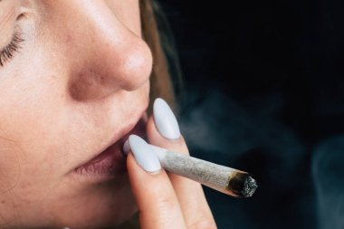 Bir kadın sigara ot esrar esrar ve onun elinde bir çakmak. Siyah bir arka plan üzerinde duman. Tıbbi esrar kullanım ve yasallaştırma esrar kavramları.