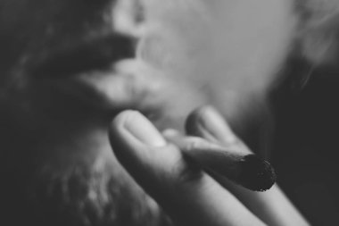 Tıbbi esrar kullanım ve yasallaştırma esrar kavramları. Siyah bir arka plan üzerinde duman. Bir adam sigara esrar esrar, esrar ve çakmak elinde. Siyah ve beyaz