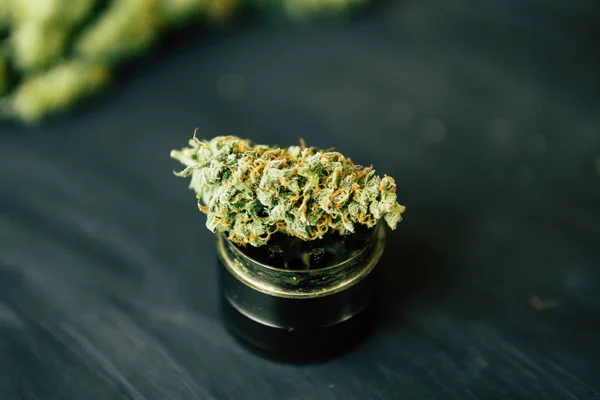 Makro marihuany s trichomy a drcené plevel v mlýnku pro sekání canapis na černý stůl — Stock fotografie
