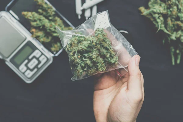 Um traficante de drogas tem um pacote de maconha em botões escuros cor vintage cannabis — Fotografia de Stock