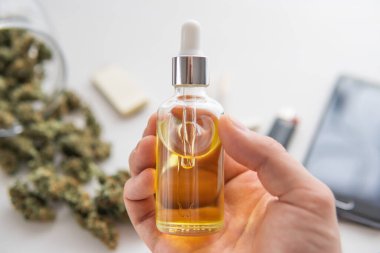 Bir şişe kenevir yağı elinde, yakın plan, tıbbi marihuana konsepti, kenevir ürünü, beyaz arka planda CBD kenevir yağı,
