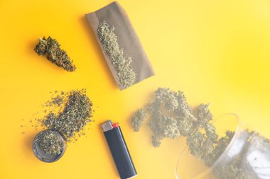 Blunt ve Lighters. Kopyalama alanı için sarı arka planda esrar tomurcukları. Üst Manzara. Kenevir tomurcukları için CBD ve THC. Kenevirin yasallaştırılması. Taze marihuana. ışık sızıntısı