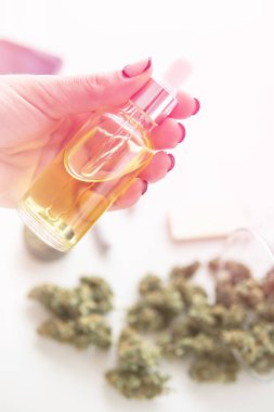 Ot ürünü, yakın plan, tıbbi kenevir konsepti, pipetli kadınların elinde yağlı kenevir CBD, beyaz arka planda marihuana özü, ışık renk tonları dikey çekim