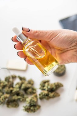 Beyaz arka planda marihuana özü, ot ürünü, yakın plan, tıbbi kenevir konsepti, pipetli kadınların elinde petrol keneviri CBD, dikey iğne