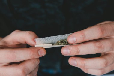 Marihuana hazırlayan ve yuvarlayan adam. Uyuşturucu narkotik konsepti. Esrarkeşin çakmakla esrar içtiği yeri kapatın. Kapatın. Uyuşturucu kullanımı. Esrar saran bir adam.
