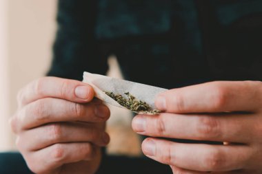 Esrar saran bir adam. Marihuana hazırlayan ve yuvarlayan adam. Uyuşturucu kullanımı. Kapatın. Esrarkeşin çakmakla esrar içtiği yeri kapatın. Uyuşturucu uyuşturucu konsepti.