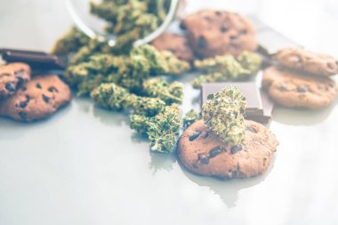 Esrarlı kurabiyeler ve masada esrar tomurcukları. Kenevir otlu kurabiyeler CBD Gıda için tıbbi marihuana tedavisi, beyaz arka plan. ışık sızıntısı