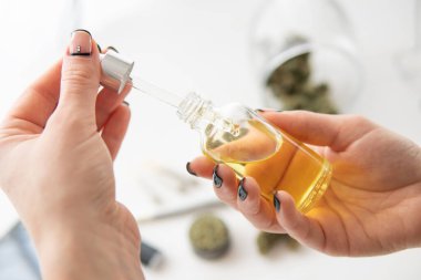 Petrol esrarı kadın eli, tıbbi kenevir konsepti, yakın plan, ot ürünü, beyaz arka planda marihuana özü,