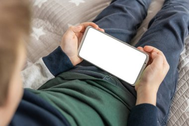 Elinde beyaz perde olan akıllı bir telefon, çocuk. Model için telefon et, çocuğu tutuyor. Akıllı telefon, elinde bir çocuğun maketi var. en üstteki görünüm