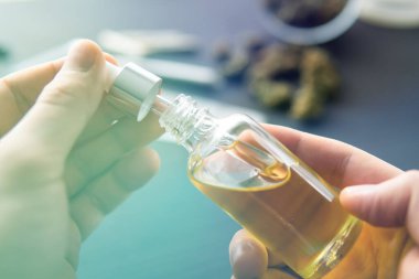Pipette bir şişe kenevir yağı, yakın plan, doğal ot, tıbbi marihuana konsepti, CBD kenevir yağı. kenevir ürünü, ışık renk tonları sızdırıyor