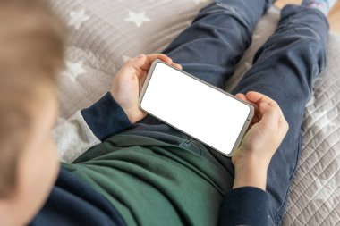 Elinde beyaz perde olan akıllı bir telefon, çocuk. Model için telefon et, çocuğu tutuyor. Akıllı telefon, elinde bir çocuğun maketi var. en üstteki görünüm
