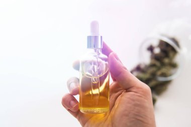 Bir şişe kenevir yağı elinde, yakın plan, kenevir ürünü, tıbbi marihuana konsepti, CBD kenevir yağı. ışık renk tonlarını sızdırır