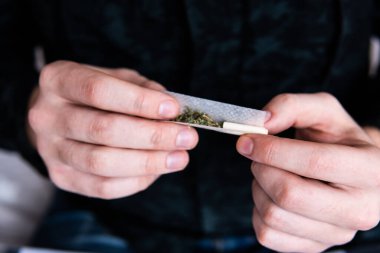Esrar saran bir adam. Marihuana hazırlayan ve yuvarlayan adam. Uyuşturucu narkotik konsepti. Esrarkeşin çakmakla esrar içtiği yeri kapatın. Kapatın. Uyuşturucu kullanımı.