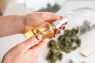 Tıbbi kenevir konsepti, beyaz arka planda marihuana özü, ot ürünü, pipette kadın elinde petrol keneviri CBD, kapat,
