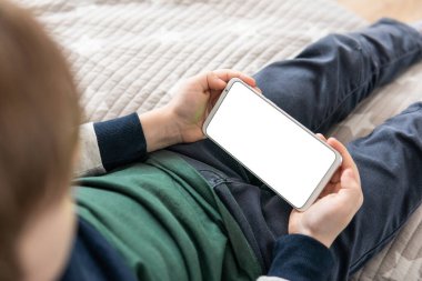 Elinde beyaz perde olan akıllı bir telefon, çocuk. Model için telefon et, çocuğu tutuyor. Akıllı telefon, elinde bir çocuğun maketi var. Üst görünüm kapat