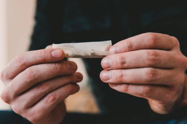 Esrarkeşin çakmakla esrar içtiği yeri kapatın. Uyuşturucu kullanımı. Kapatın. Uyuşturucu narkotik konsepti. Esrar saran bir adam. Marihuana hazırlayan ve yuvarlayan adam.