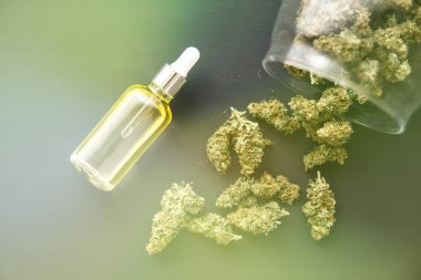 Esrar konsepti, yakın plan, CBD medikal petrol, pipetteki kenevir yağı, ışık renk tonlarından sızar