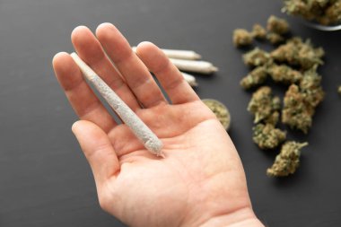 Esrarla el birliğinde, öğütücüde taze marihuana, üst manzarada, siyah masada esrar tomurcukları,