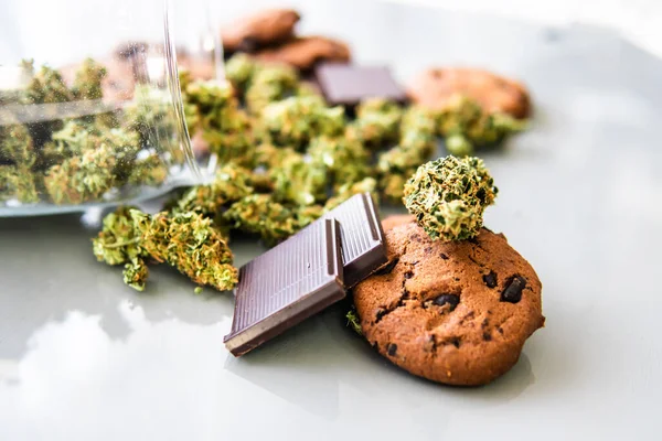 Treatment of medical marijuana for use in food, white background. Cookies with cannabis and buds of marijuana on the table. Cookies with cannabis herb CBD.