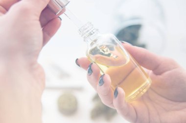 Tıbbi kenevir konsepti, beyaz arka planda marihuana özü, pipetli kadınların elinde yağlı kenevir CBD, ot ürünü, kapat, ışık renk tonlarından sızar